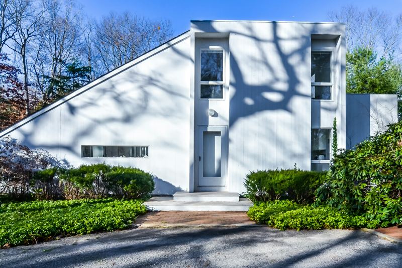 White-clad modern house with clipped hedges and a gravel drive