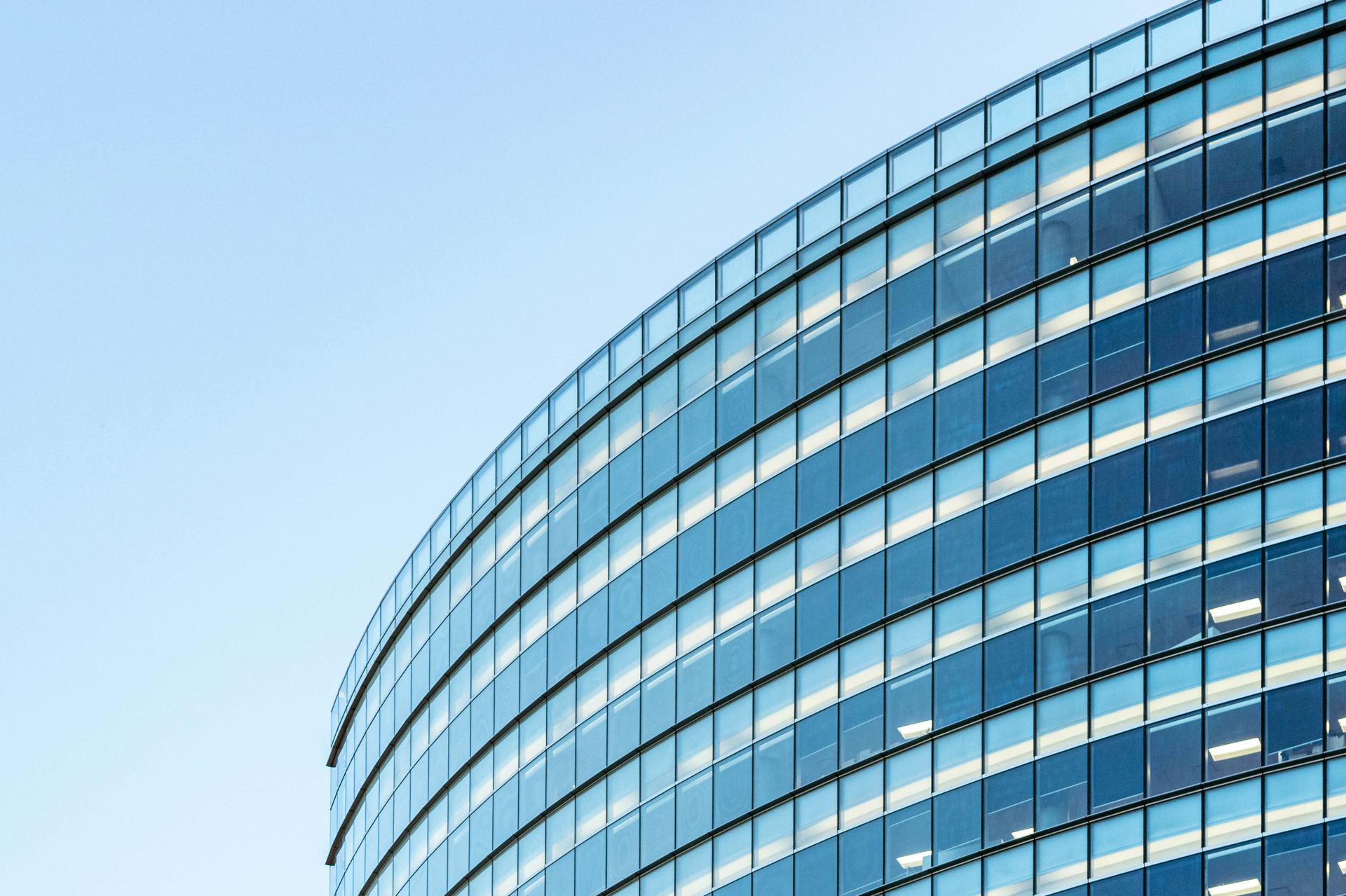 Curved glass curtain wall of a high-rise office tower against a clear sky