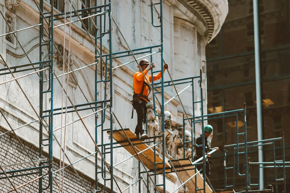 Workers on scaffolding examining a masonry facade during a failure investigation