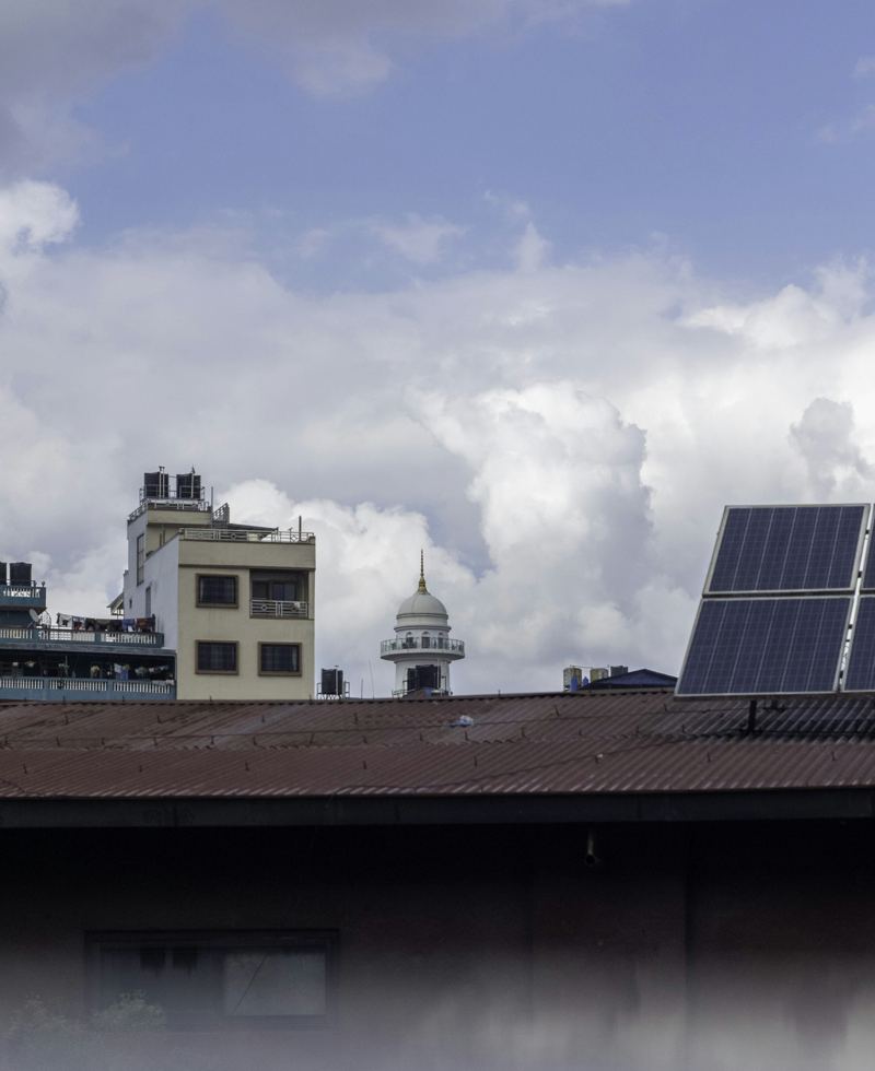 Solar panels mounted on an existing city rooftop alongside mechanical equipment